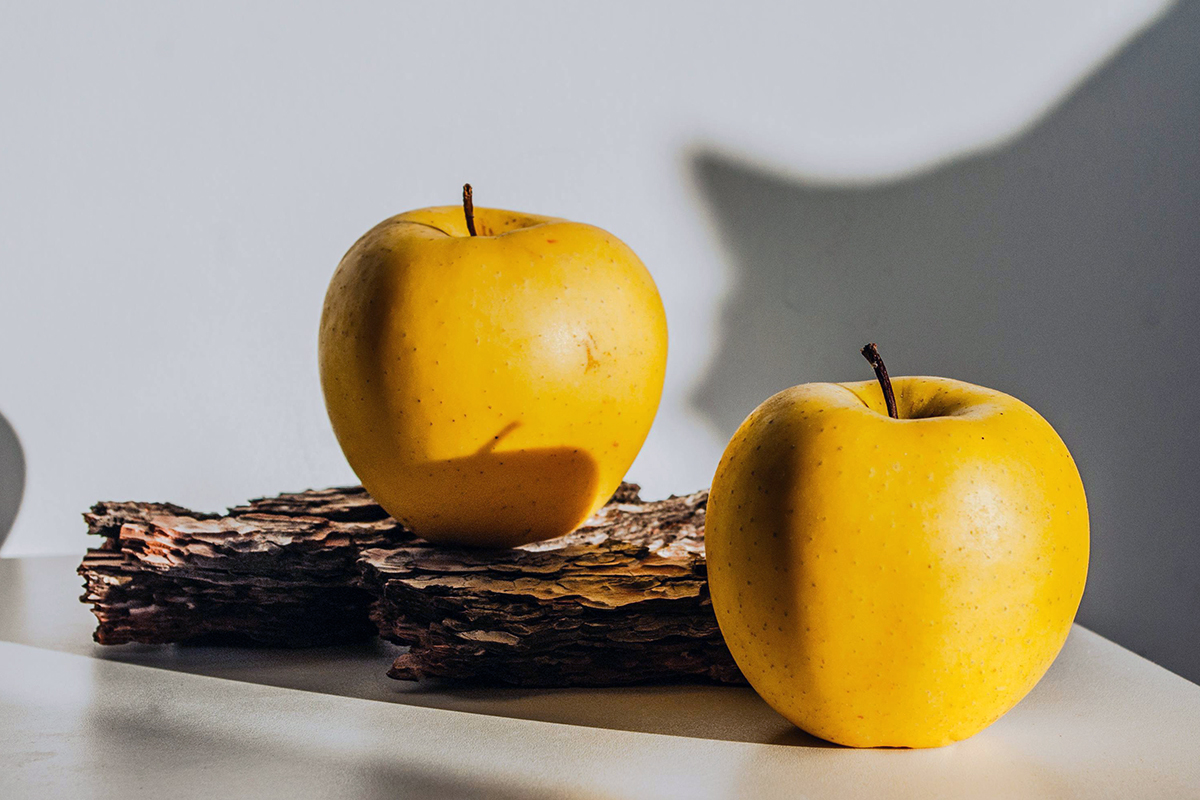 Two yellow apples on a countertop.