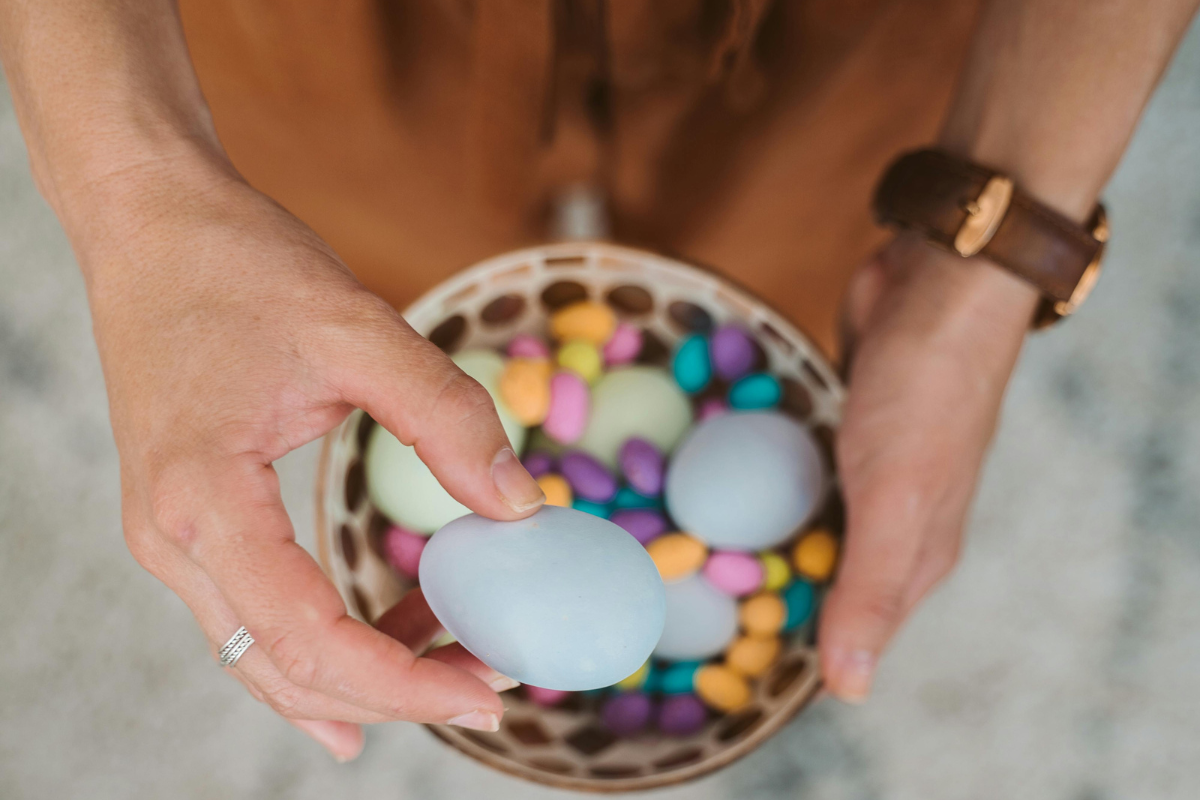 A person taking an egg from a basket of eggs