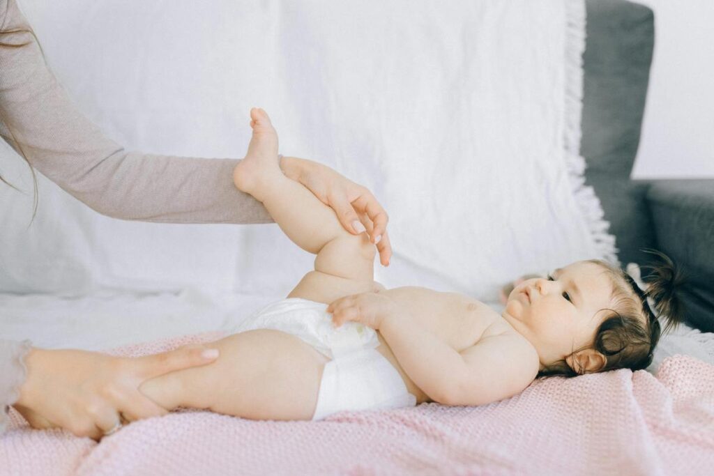 A parent holding and stretching the baby's legs
