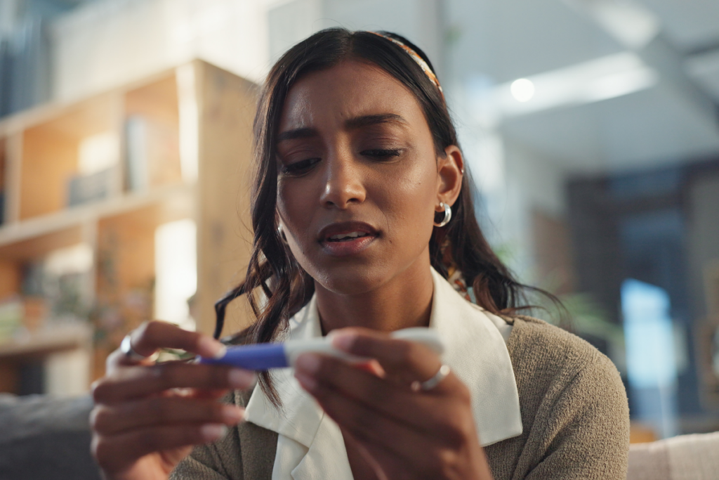 A person looking at a pregnancy test disappointed.