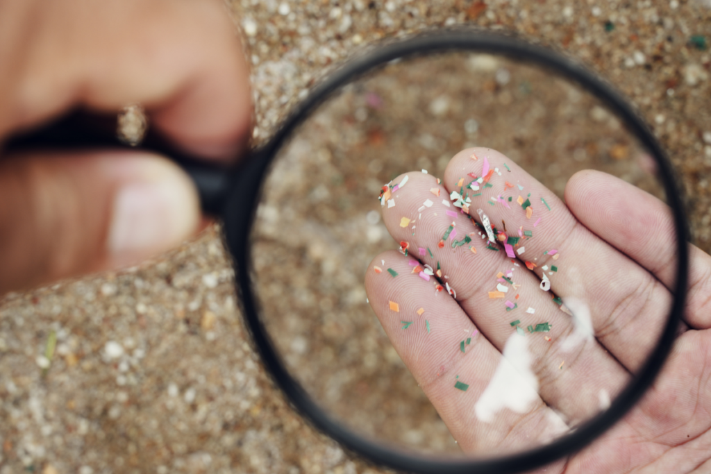 Microplastics in the sand seen through magnifying glass