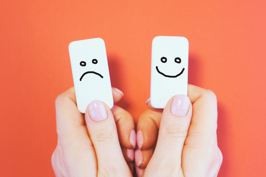 Two hands holding a happy face chip and a sad face chip.