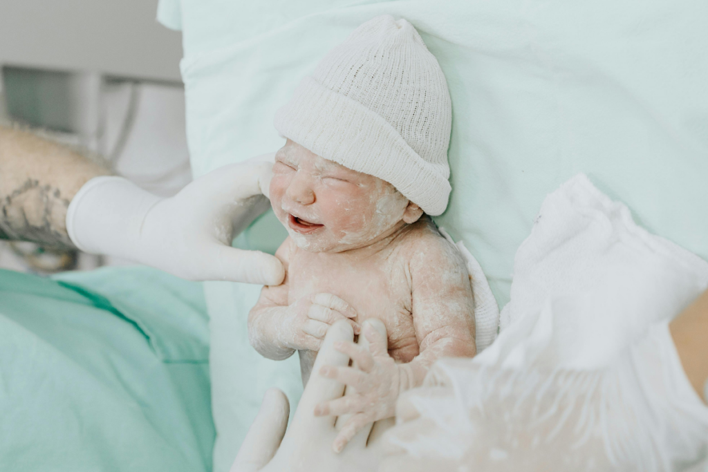 Gloved hands touching a newborn baby in labor room