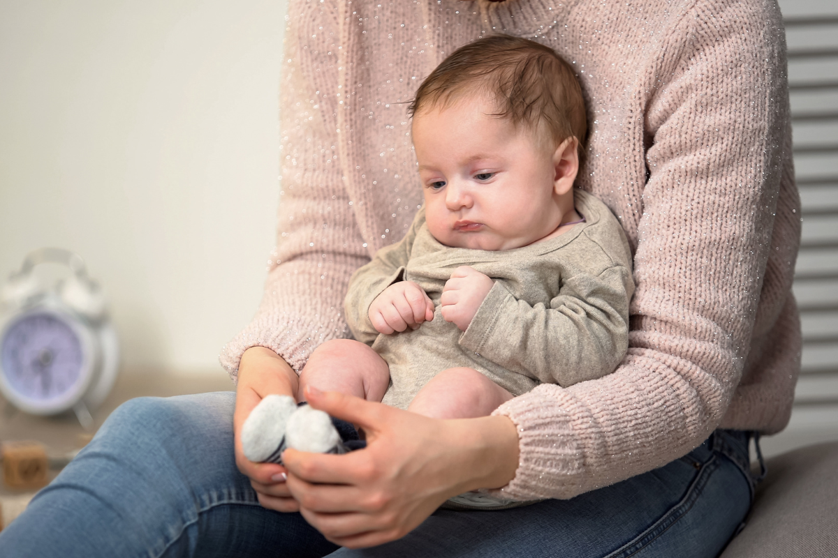 A baby sitting on a parent's lap.