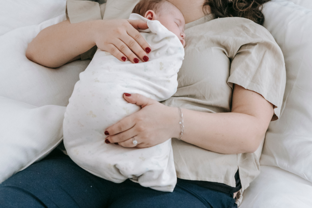 A baby lying on a sleeping parent's chest.