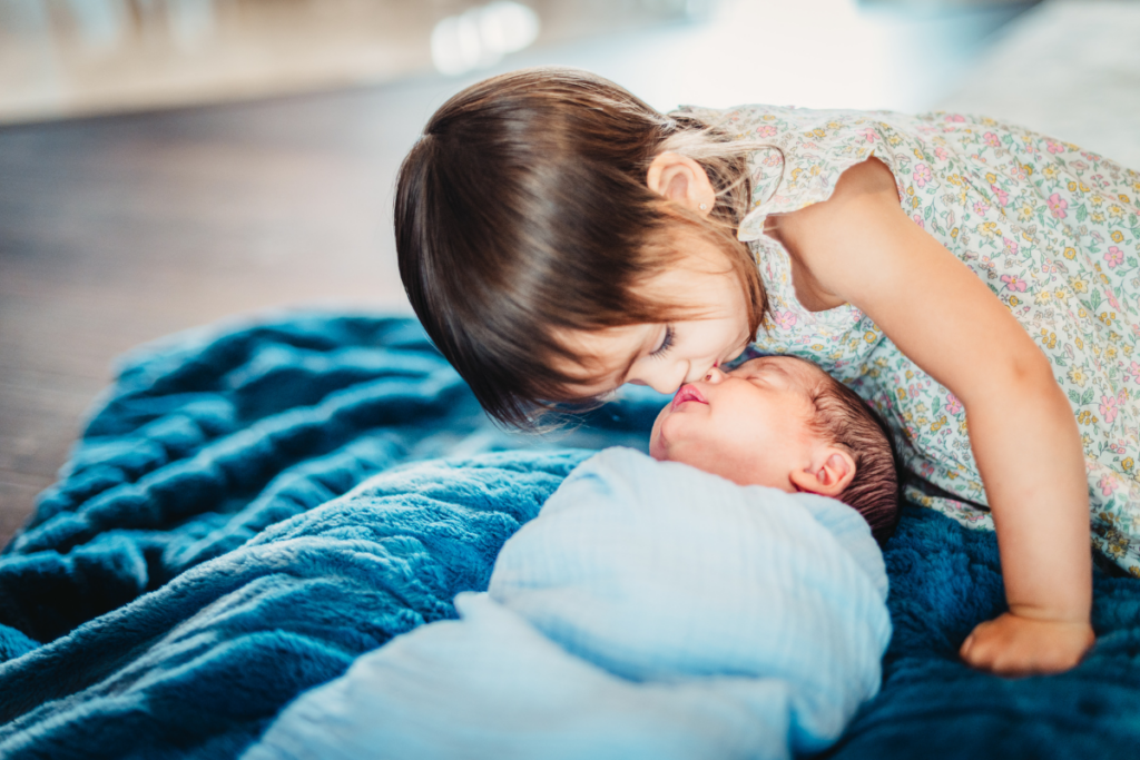 A child kissing the forehead of her baby sibling.