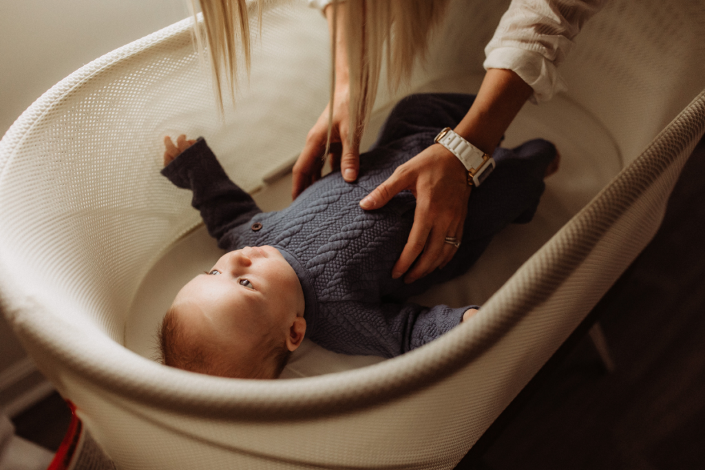 A parent lifting a baby from the bassinet.