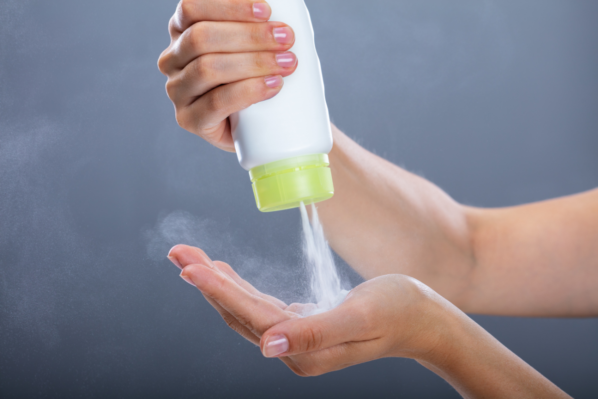 A person pumping talcum powder in hand.