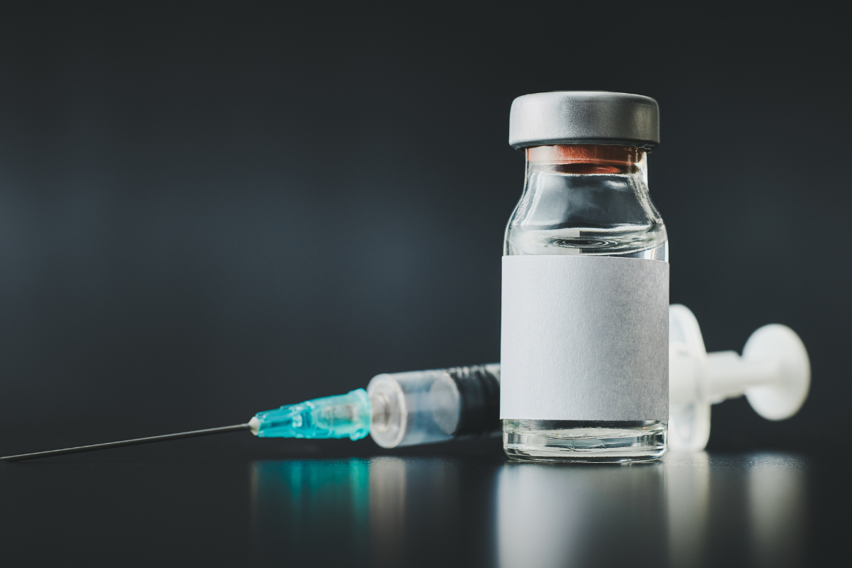 Syringe and vaccine vial on a dark background