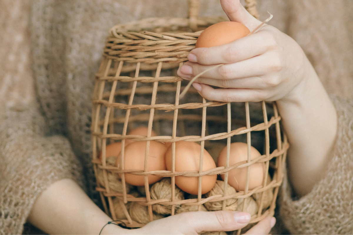 A person holding a basket of eggs.