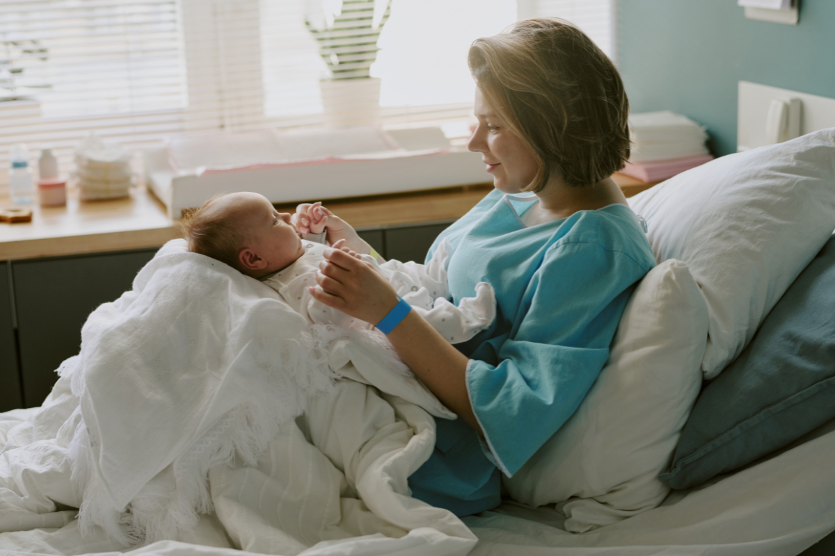 A new mom playing with her newborn in a hospital.