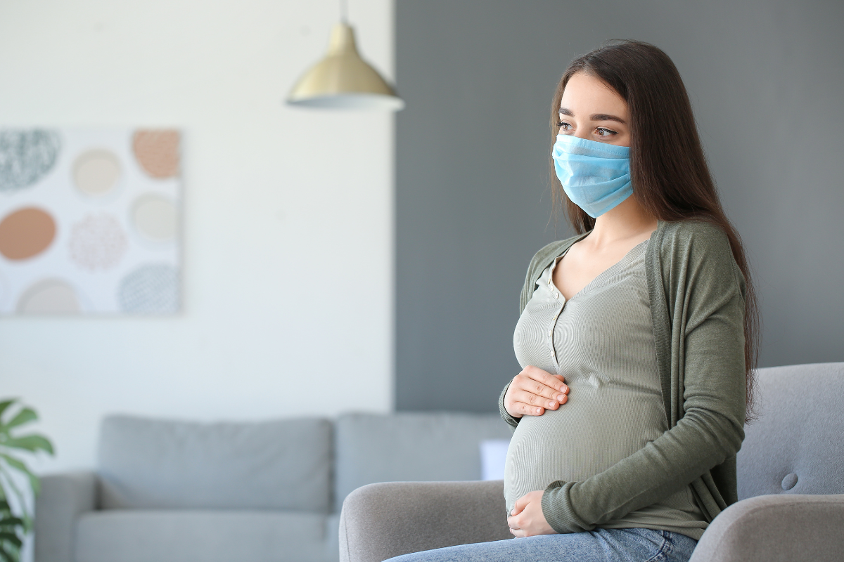 A pregnant person wearing a mask.