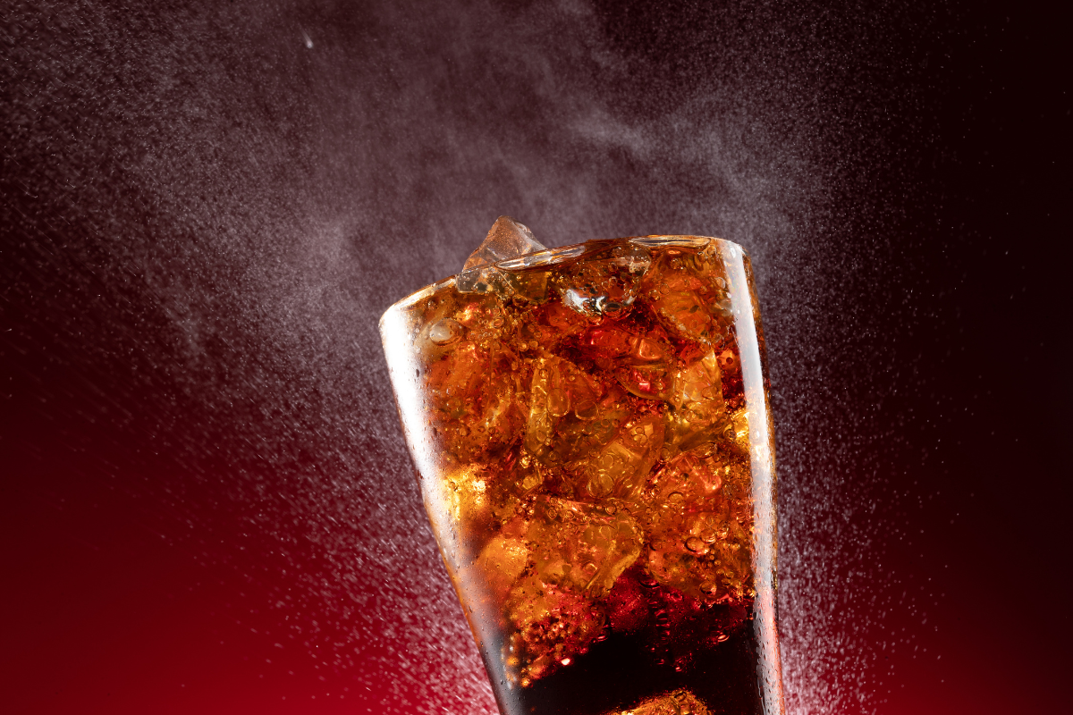 A diet coke in a glass with ice cubes.