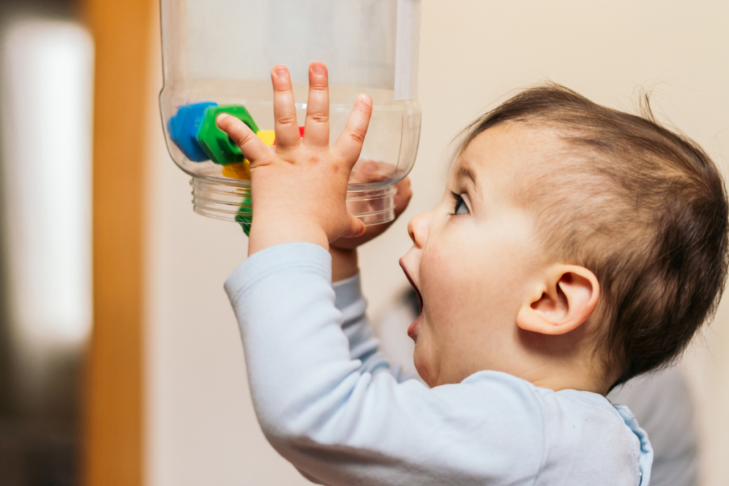 A toddler trying to empty a jar.