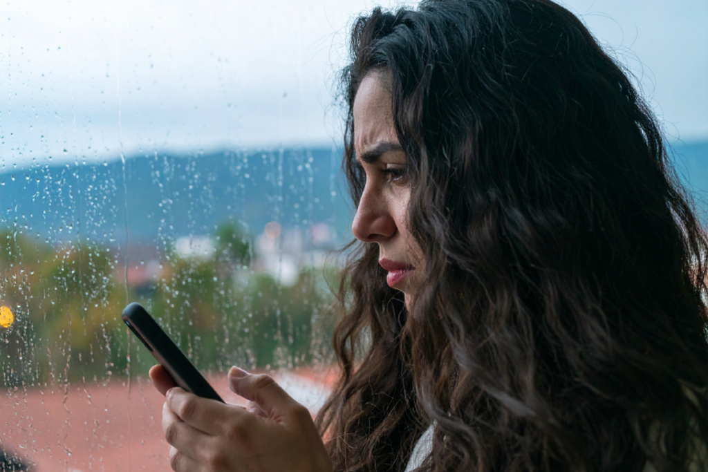 A person looking stressed and browsing through phone.